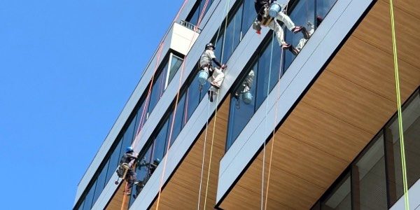 ビルの高所ガラスを清掃するKanoNのスタッフ