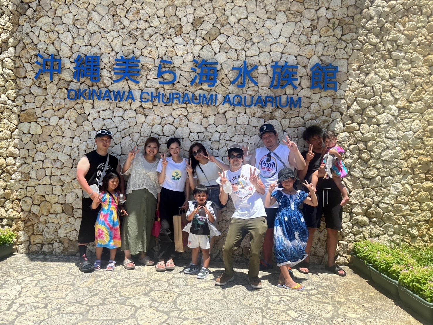 沖縄の社員旅行 美ら海水族館の前で家族と集合写真